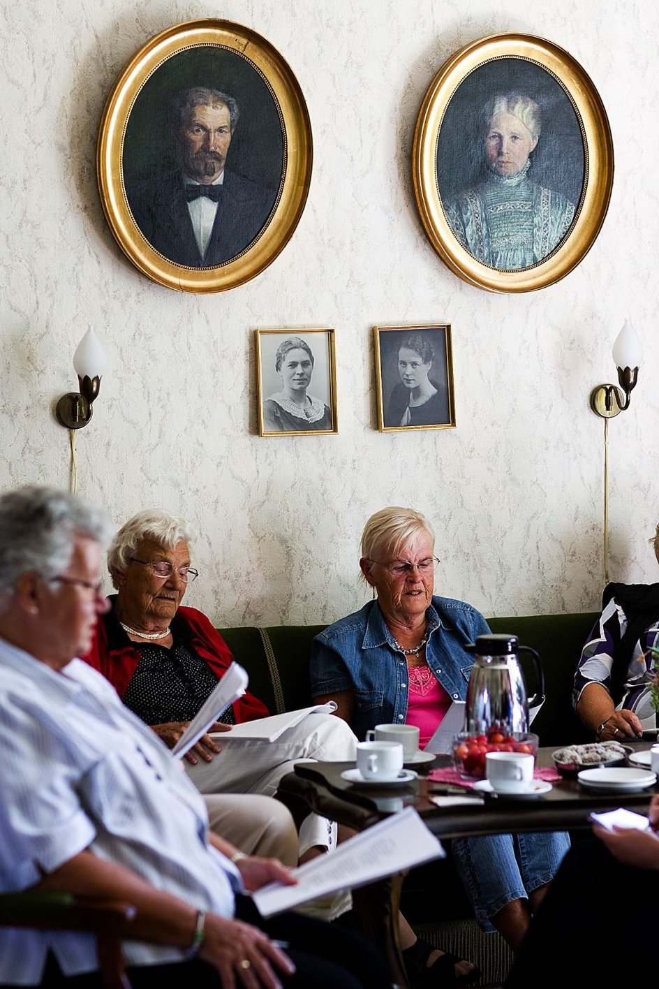 Enkerne sætter pris på fællessang under ferien. På væggen lytter villaens tidligere beboere med fra deres guldrammer. I de ovale billeder er det købmandsparret J.C. og Kirstine Albertsen. --