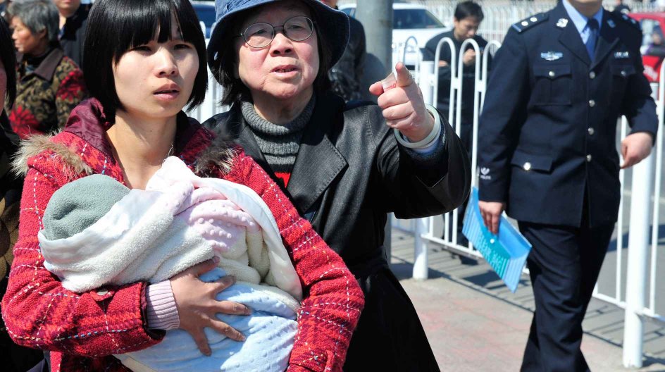 Zeng Jinyan (L), the wife of human rights activist Hu Jia holds her baby as she walks with Hu's mother (C) while a Chinese policeman follows behind, outside a courthouse in Beijing on April 3, 2008. Activist Hu Jia was on April 3 jailed for three years and six months for subversion, his lawyer said, amid what rights groups charge is a campaign by China to silence dissent before the Olympics. AFP PHOTO/TEH ENG KOON