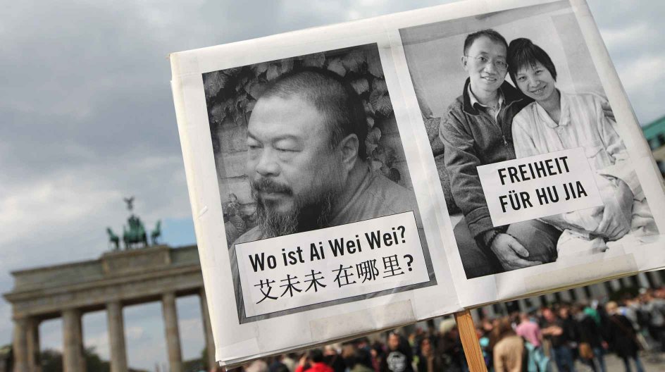 An Amnesty International activist holds a sign with a picture of Ai Weiwei and Hu Jia on it in front of the Brandenburg Gate in Berlin on April 16, 2011. Members and supporters of Amnesty International gathered together for a vigil with the motto "Where is Ai Weiwei?" because it is still not clear where the Chinese artist is being held. AFP PHOTO / FLORIAN SCHUH GERMANY OUT