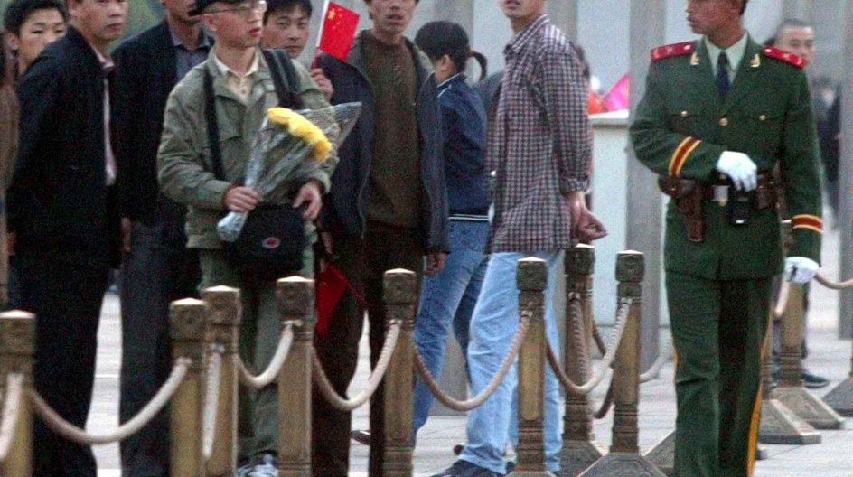 A Chinese paramilitary officer eyes Hu Jia, a Beijing-based AIDS activist, who attempted to lay flowers before the Monument to the People's Heroes in memory of the 15th death anniversary of former Chinese leader Hu Yaobang on Tiananmen Square in Beijing, China, in this Thursday, April 15, 2004 photo. A United Nations agency said Tuesday it has expressed concern to the Chinese government about the possible detention of Hu, who disappeared after staging a hunger strike to protest violence against....