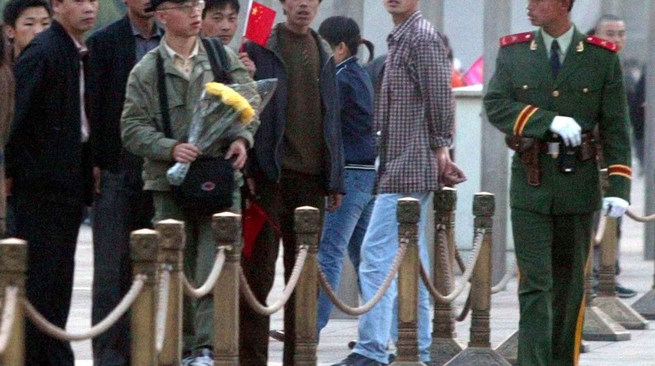 A Chinese paramilitary officer eyes Hu Jia, a Beijing-based AIDS activist, who attempted to lay flowers before the Monument to the People's Heroes in memory of the 15th death anniversary of former Chinese leader Hu Yaobang on Tiananmen Square in Beijing, China, in this Thursday, April 15, 2004 photo.  A United Nations agency said Tuesday it has expressed concern to the Chinese government about the possible detention of Hu, who disappeared after staging a hunger strike to protest violence against....