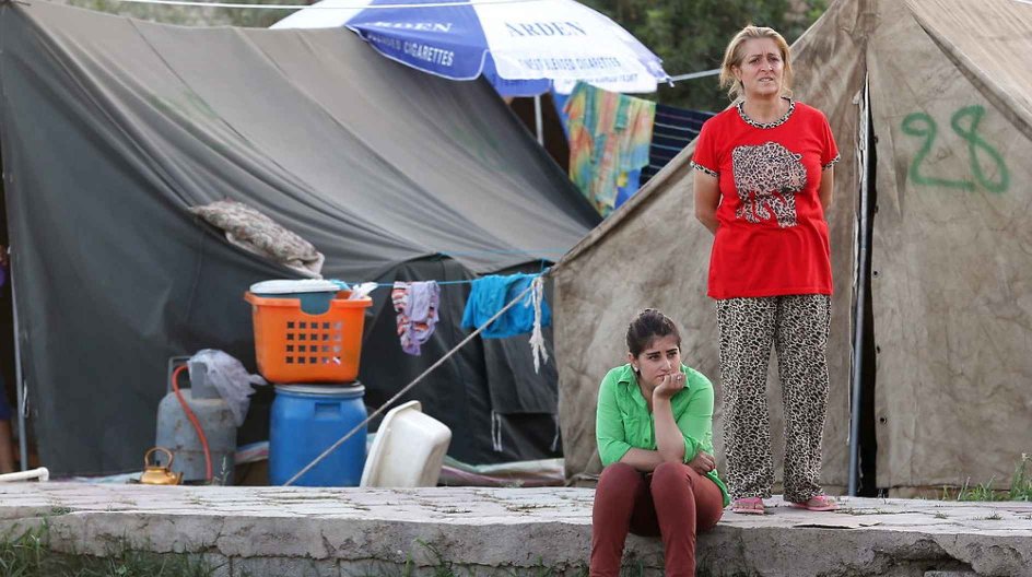 epa04394451 Two Iraqi Christian women from Qaraqosh, who were forced to flee from advancing Islamic State (IS) militants in Mosul, wait in front of tents in the Bahrka Refugee camp at the Mar Joseph shrine in Ankawa, north of Erbil city, northern Iraq, 10 September 2014. The Qaraqosh Christians were driven from their land and their property which is now feared in the hands of the IS militants. An estimate 100, 000 to 200, 000 people have fled the region, most of them to the Kurdistan capital Erb....