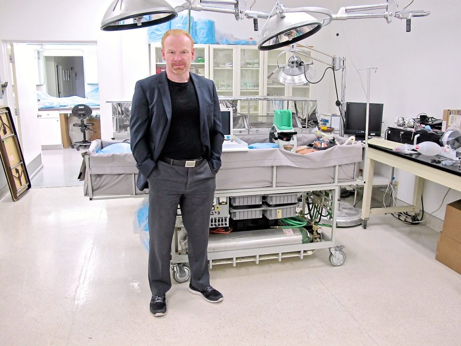 ”Hvis du tror på himlen, kan det måske synes mindre vigtigt at forlænge din tid her på Jorden. Men selv hvis du er religiøs, ser jeg ingen hindring for, at du skulle afvise en radikal procedure, der kan redde dit liv. Vi tilbyder ikke evigt liv. Kryopræservering er blot en livsforlængende teknologi på samme måde, som kunstigt åndedræt er det,” siger den britiskfødte filosof og futurist Max More, der er direktør for Alcor. Her ses han i operationsrummet, hvor genstanden i båren er en dukke brugt til undervisning.