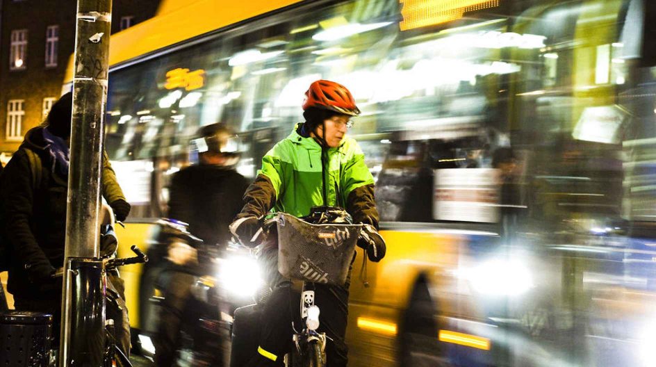 Cyklister på cykelstien i myldretiden. Her holder dame med rød cykelhjelm tilbage for bussen