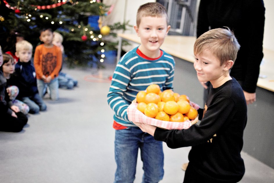 Elever fra 2.b bærer appelsiner ind til tilskuerne. 