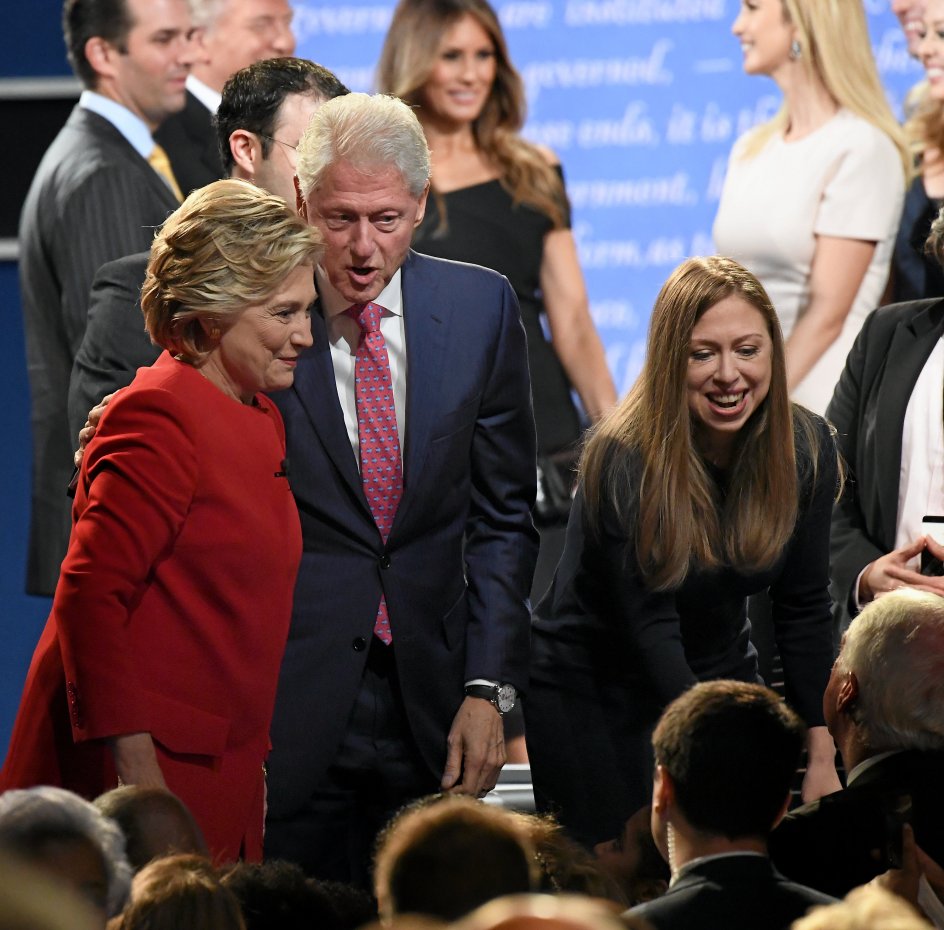 Hillary Clinton, hendes mand Bill Clinton og datteren Chelsea Clinton hilser på publikum på Hofstra University i delstaten New York efter den første af de tre tv-debatter mellem den demokratiske præsidentkandidat og hendes republikanske rival, Donald Trump, der skimtes i baggrunden sammen med sin familie. –