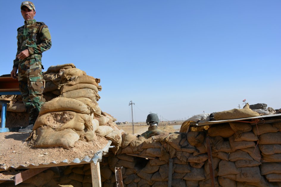 En yazidi i peshmerga-uniform ses her ved frontlinjen til shia-militsen Hashd al-Shaabi syd for Sinjar. En dukke er sat op på den anden side af sandsækkene. I ingenmandsland, midt mellem frontlinjerne, har man fundet en massegrav med knogler fra folkedrabet på yazidierne i 2014, men de stridende parter kan ikke blive enige om, hvem der skal undersøge massegraven. –