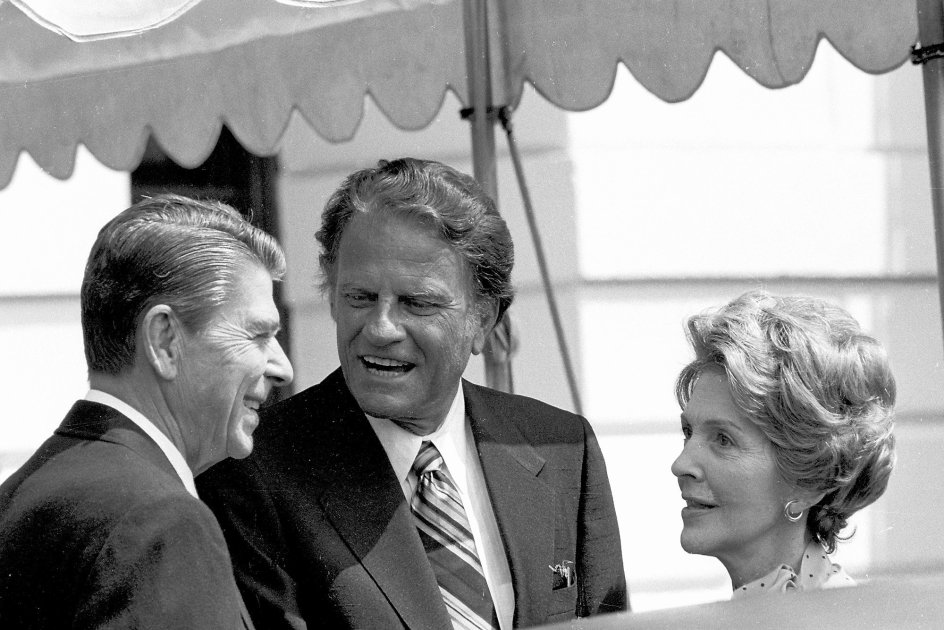 Billy Graham taler med præsident Ronald Reagan og førstedamen Nancy Reagan i Det Hvide Hus i 1981. Selv var han i en overgang medlem af Det Demokratiske Parti, men sagde også, at ” ”Jeg tror ikke, at Jesus eller apostlene valgte side i deres tids politiske arenaer.” – 