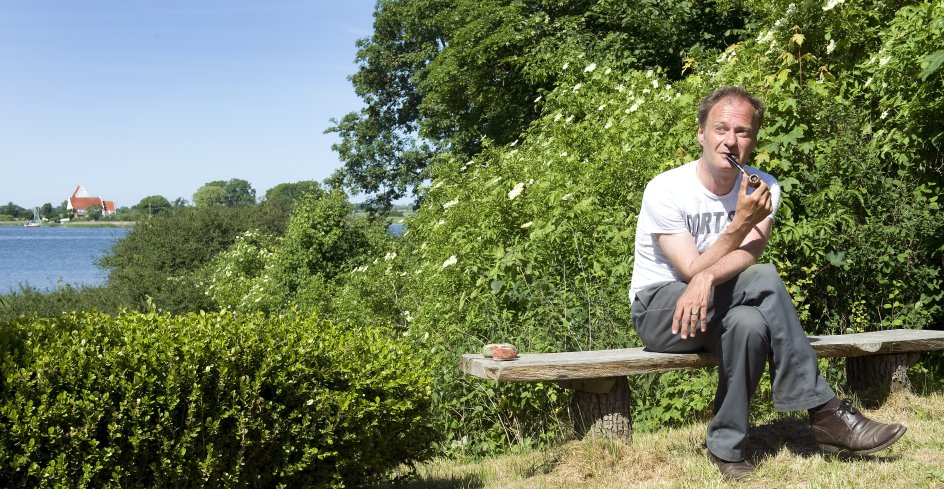 Fra sit sommerhus i Kragevig på Sydsjælland har Knud Romer udsigt til Jungshoved Kirke, der ”står hvid og fin på den anden side af vigen med en lille havn”, som han skriver i sin nye roman ”Kort over paradis”. Det er også dér, han en dag skal begraves, fortæller han – tæt på fuglekvidder og barndommens Falster. –