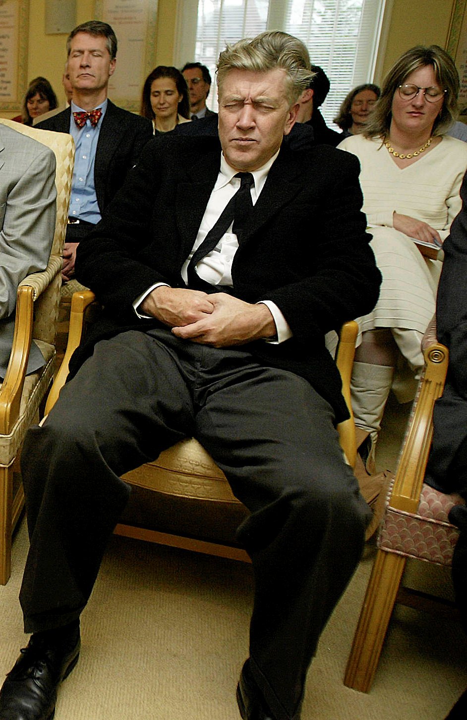Her ses den amerikanske filminstruktør David Lynch i 2003 under en meditation i guruen Maharishi Mahesh Yogis Peace Palace i Maryland, USA. Han er et af de mest kendte TM- medlemmer i dag og var i 2005 var med til at stifte en TM-fond, som arbejder for bevidsthedsfokuseret undervisning til børn og voksne samt verdensfred. –
