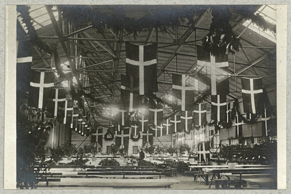 Sjældent før eller siden er der blevet flaget så meget med Dannebrog som ved Genforeningen i 1920. Her er en hal gjort klar til genforeningsfest. - Foto: Johs. Timm/Det Kongelige Biblioteks Billedsamling.