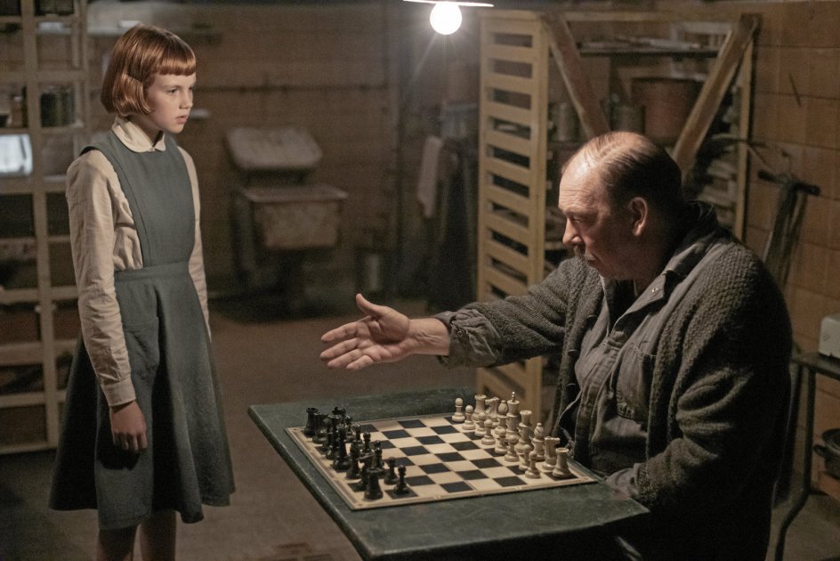 Beth Harmon (Isla Johnston) støder i ”Dronninggambit” første gang på et skakspil i børnehjemmets kælder, hvor viceværten Hr. Shaibel (Bill Camp) holder til. – Foto: Phil Bray/Netflix.