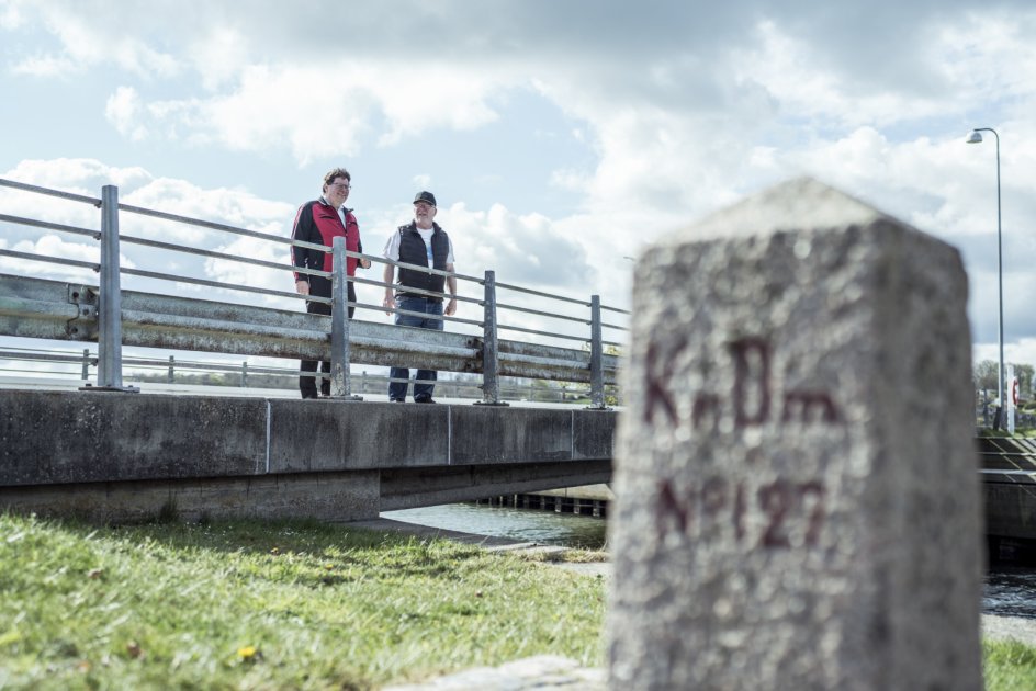 Grænseentusiasterne Hans Peter Nissen (tv.) og Peter Tagesen (th.) på broen over indløbet ved Hejlsminde Nor. Før Genforeningen i 1920 gik grænsen lige præcis midtfor broen, der dengang ikke var bygget. Man skulle med en færge over for at komme til Danmark, og det lykkedes Hans Peter Nissens morfar, der i 1916 flygtede fra tysk militærtjeneste.