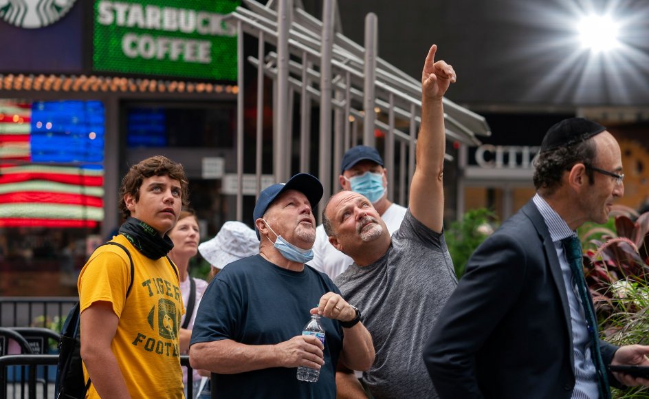En gruppe mennesker følger milliardæren Jeff Bezos rumrejse på en skærm på Times Square i New York.