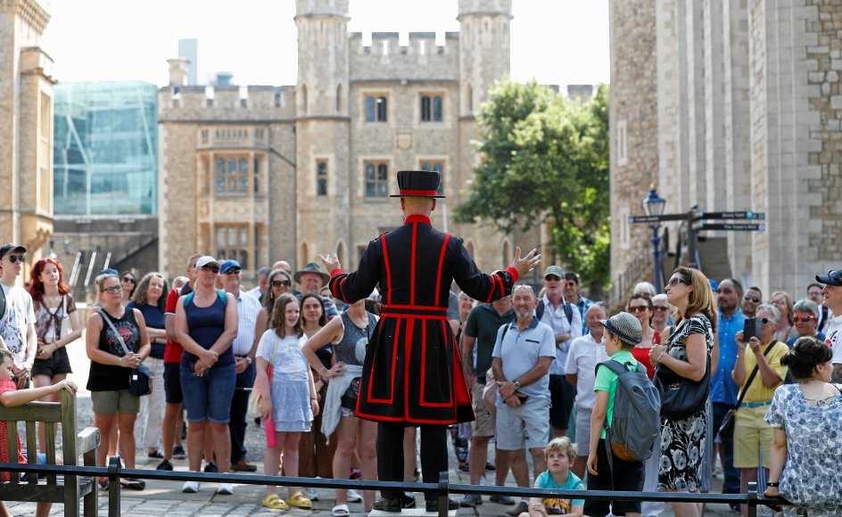 På frihedsdagen var fremmødet også stort ved turistattraktioner som Tower of London, hvor Yeoman-vagten Barney Chandler her taler til det første hold uden mundbind, der deltager i den første Beefeater-rundtur i 16 måneder. – Foto: Peter Nicholls/Reuters/Ritzau Scanpix.