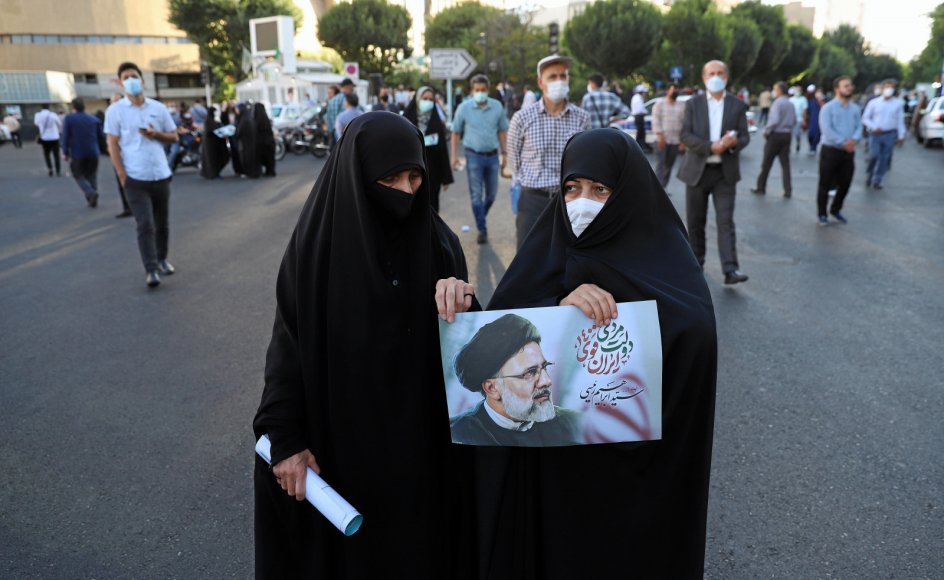 To iranske kvinder holder plakat af deres favoritkandidat Ebrahim Raisi forud for dagens præsidentvalg. På grund af stor intern utilfredshed med regimet ventes valgdeltagelsen ikke at komme over 40 procent af de 59 millioner iranere med stemmeret.