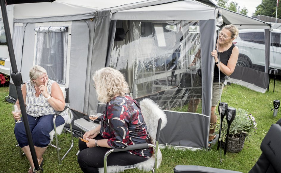 54-årige Randi Larsen (til højre) har inviteret nabocampisterne 56-årige Ulla Pedersen (til venstre) og 56-årige Dorthe Find (i midten) forbi til et koldt glas i skyggen. De tre kvinder og deres mænd er med årene blevet en sammentømret gruppe, som tilbringer store dele af sommeren sammen og holder kontakten, når sæsonen er slut.