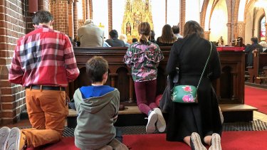 Her ses knælende kirkegængere under den dansk-sprogede messe i Sankt Albani Kirke i Odense.