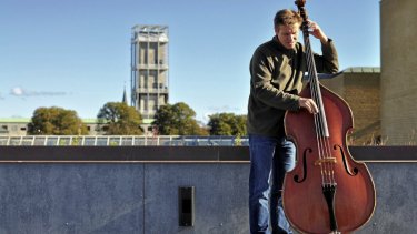 Peter Vuust er født i Aarhus og har boet i byen hele sit liv. Hver morgen øver han sig i 45 minutter på sin kontrabas hjemme i forstadskvarteret Åbyhøj. Her er han fotograferet med Aarhus’ ikoniske rådhus i baggrunden.